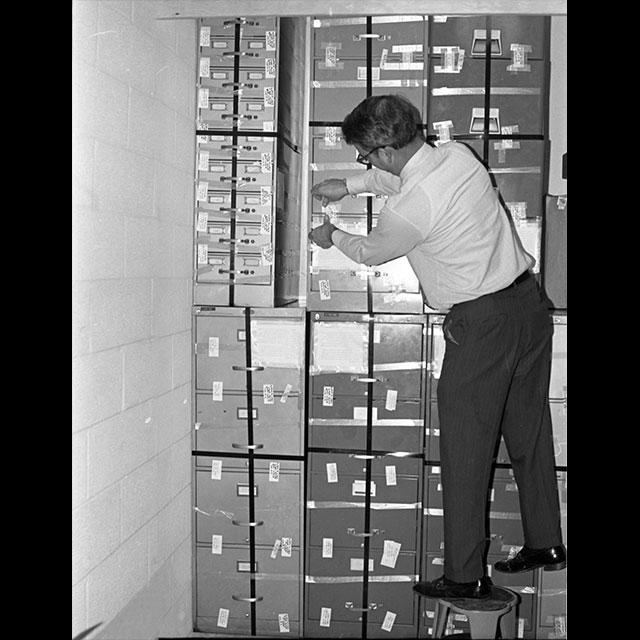 A black and white photograph of MDAH director emeritus Elbert Hilliard labeling stacks of Sovereignty Commission files