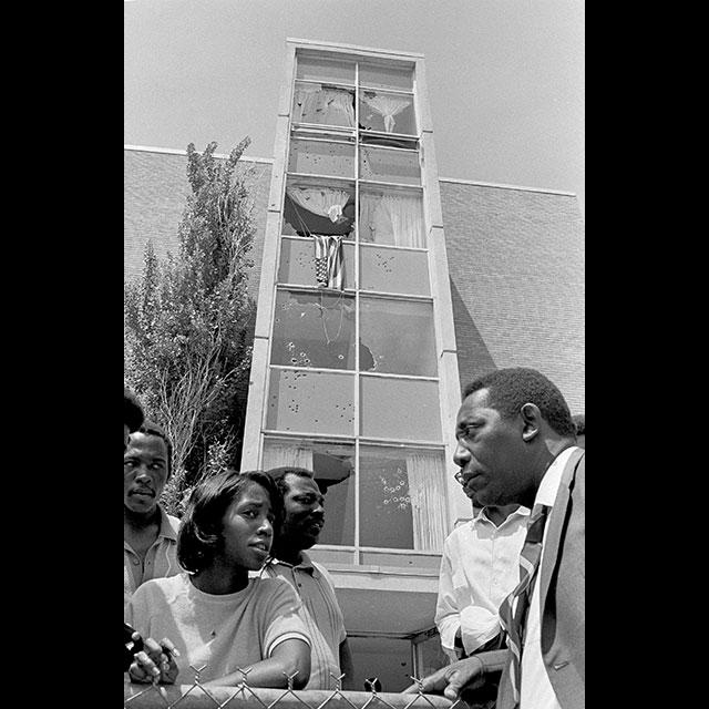A black and white photograph of Charles Evers speaking with Jackson State students after the shooting