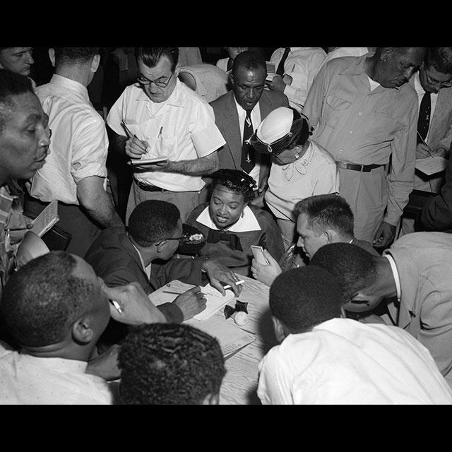 A black and white photograph of Mamie Till Mobley giving press interviews 