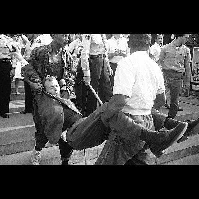 Reverend Ed King being carried to a police wagon after being arrested