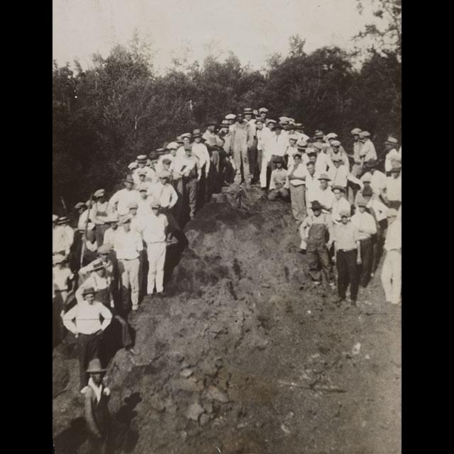 A lynch mob, all dressed in light colored or white clothes surround an area to be used as a lynching site